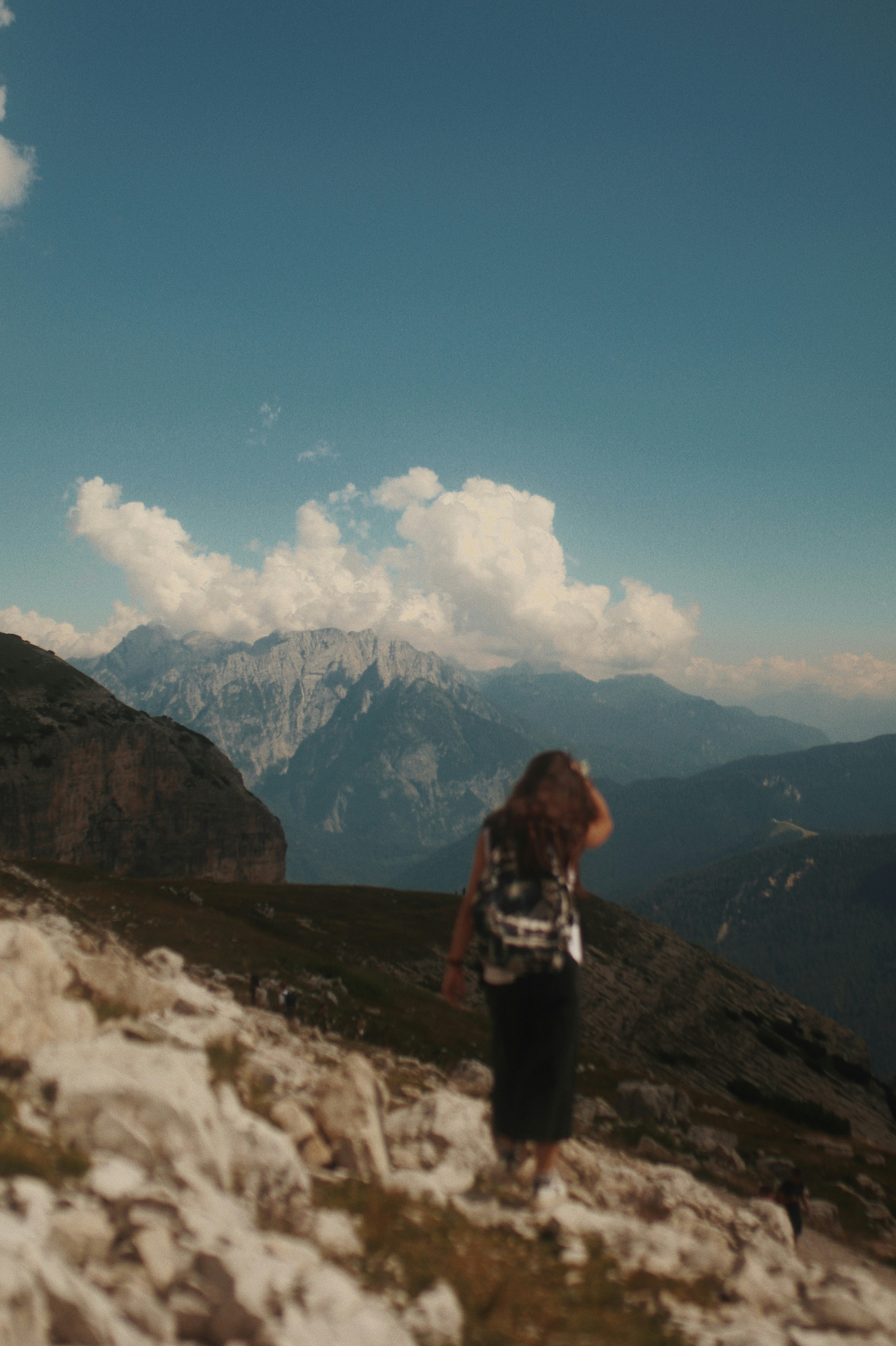 woman in black jacket standing on rock mountain under blue sky during daytime